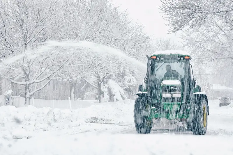 Commercial plowing clearing a large parking lot after a storm